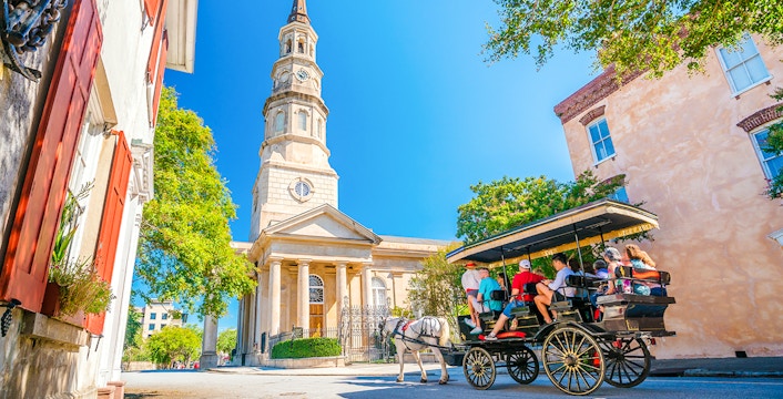 Horse-drawn carriage tour in historical downtown Charleston with a church in the background.