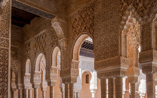 Intricate Moorish arches and carvings inside the Alhambra Palace, Granada, Spain.