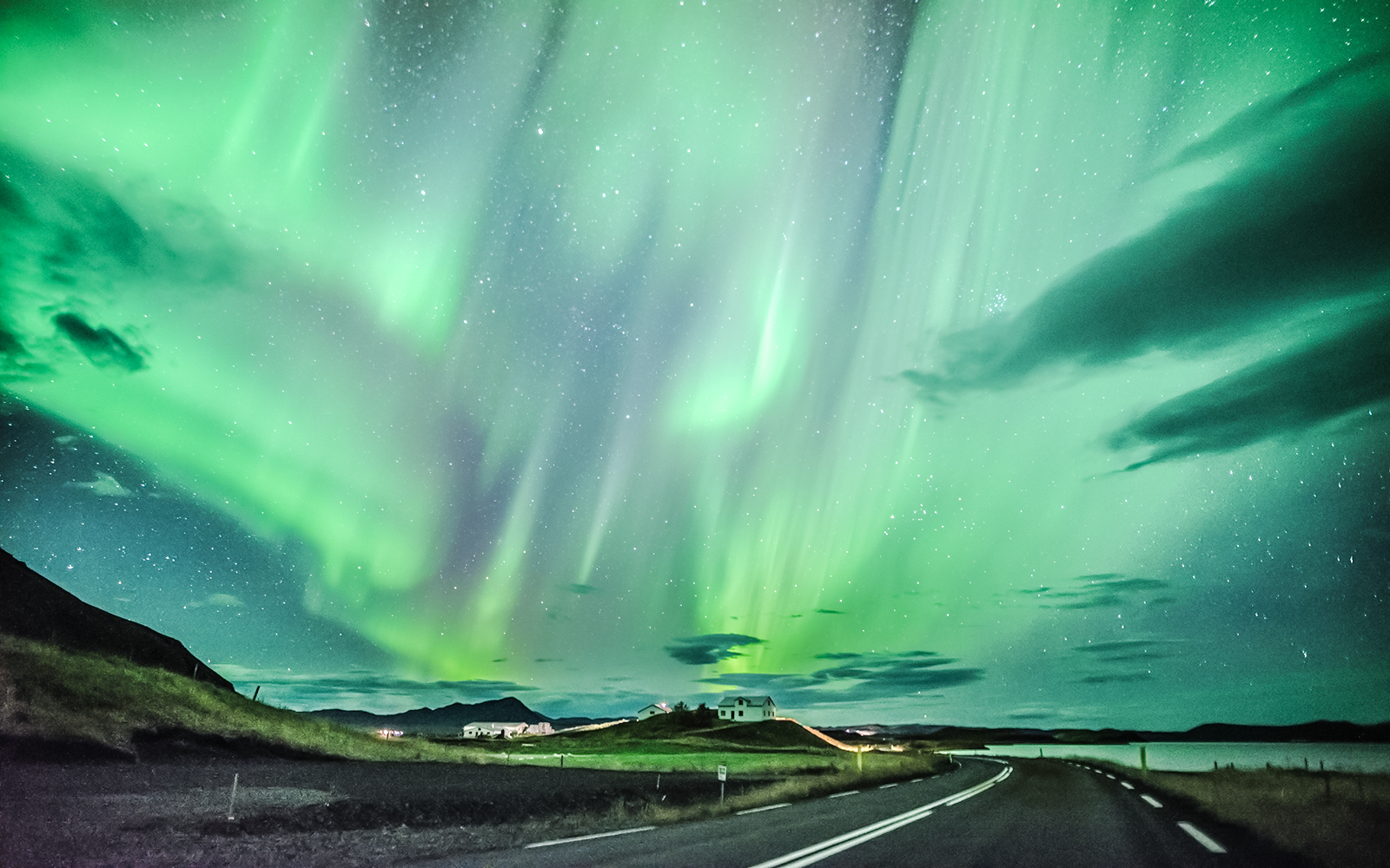 Northern lights over a rural road during Secret Lagoon Bath tour in Iceland.