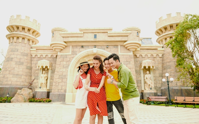 Tourists taking a selfie in front of a castle at Fairy World VinWonders.