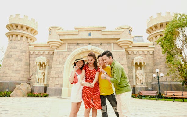 Tourists taking a selfie in front of a castle at Fairy World VinWonders.