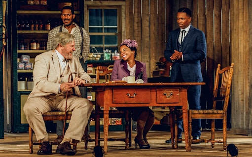 Actors performing a scene from "Purlie Victorious" in a rustic setting.