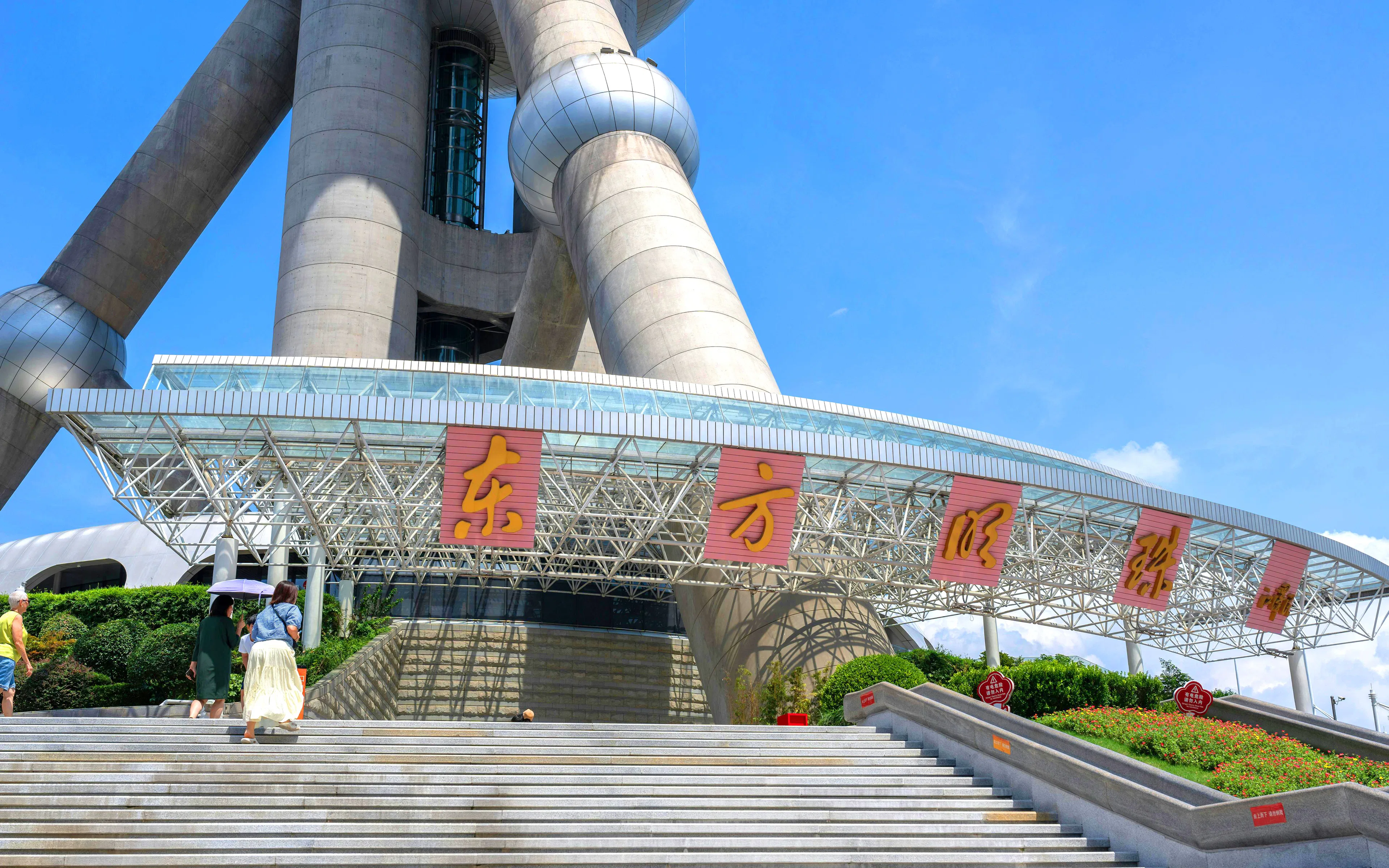 Entrance of Oriental Pearl Tower in Shanghai with visitors on steps.