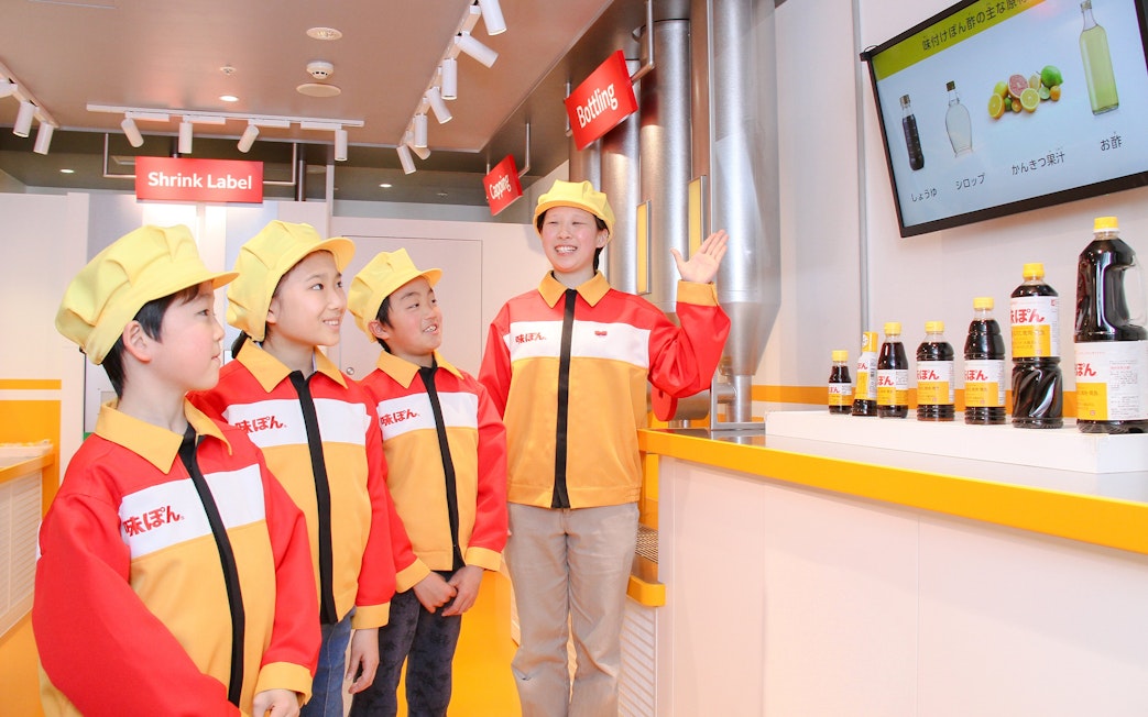 Children learning about bottling process at KidZania Tokyo demonstration.
