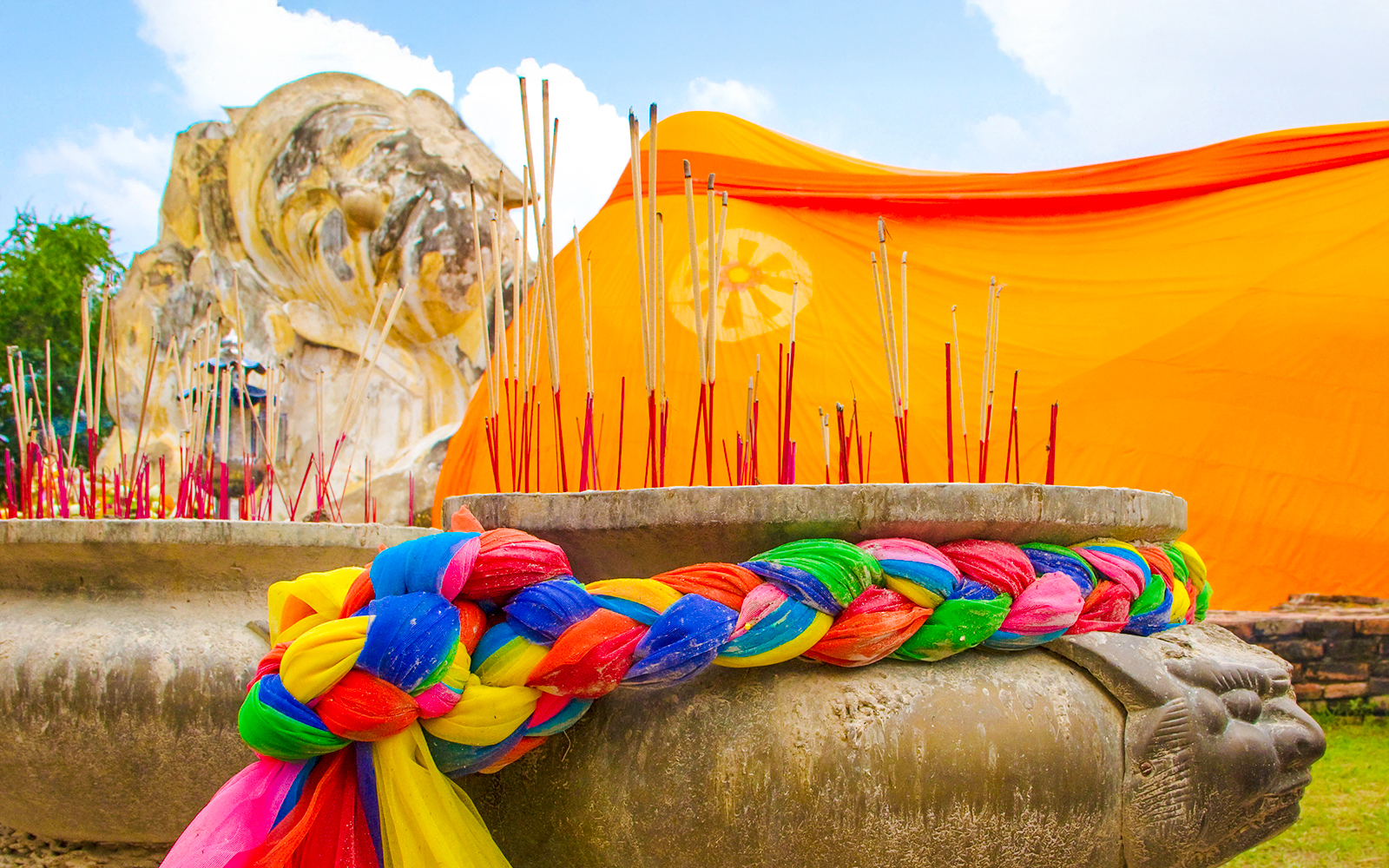 Reclining Buddha statue with incense and colorful fabric at Wat Lokayasutharam, Ayutthaya.