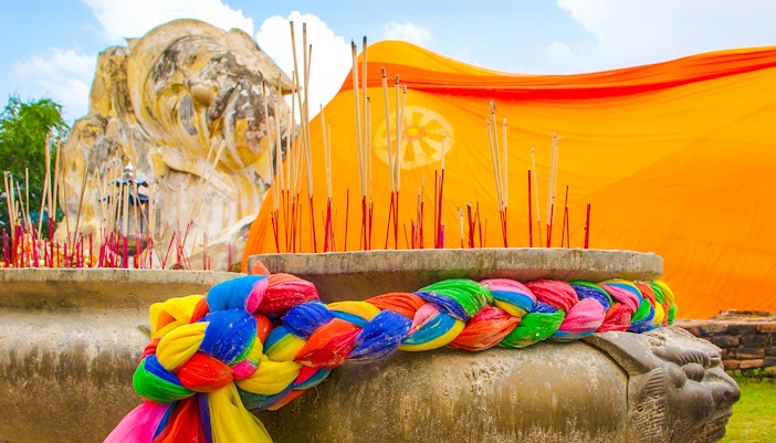 Reclining Buddha statue with incense and colorful fabric at Wat Lokayasutharam, Ayutthaya.