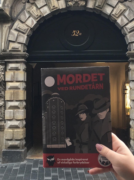 Murder Mystery Experience brochure held in front of Round Tower entrance, Copenhagen.