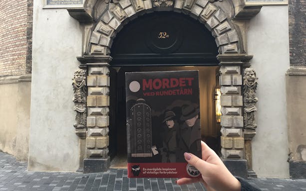 Murder Mystery Experience brochure held in front of Round Tower entrance, Copenhagen.