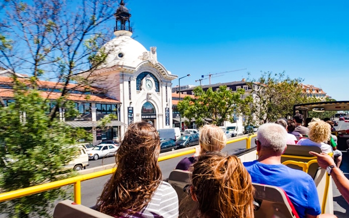 Tourists on a hop-on hop-off bus passing Mercado da Ribeira in Lisbon.