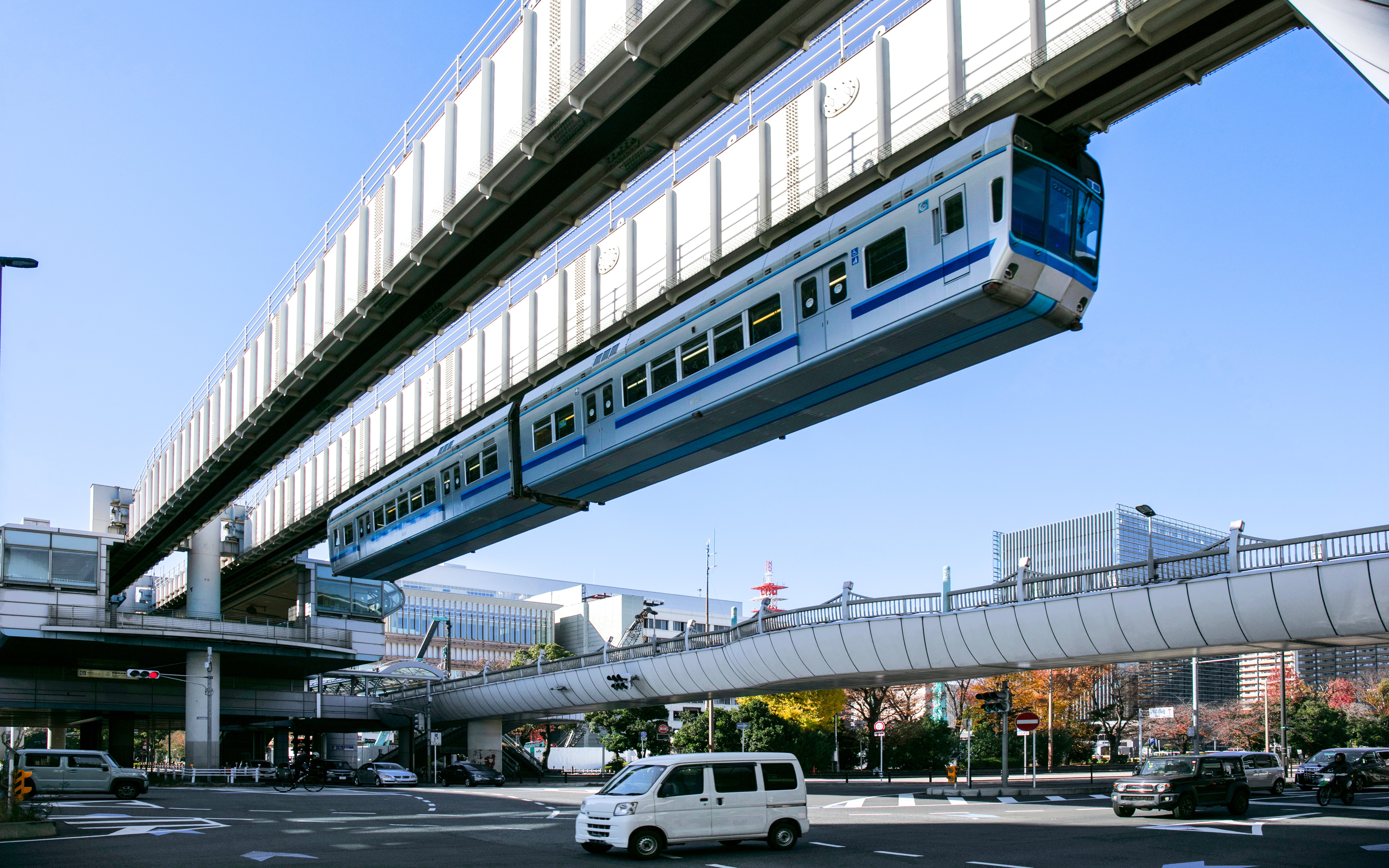 Suspended monorail train traveling above a street in Chiba, Japan.