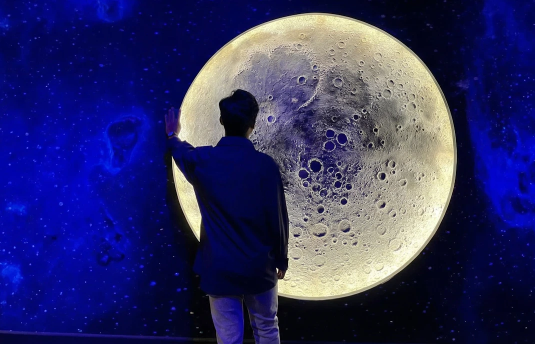 Person interacting with moon exhibit at Space Gallery, Petrosains.