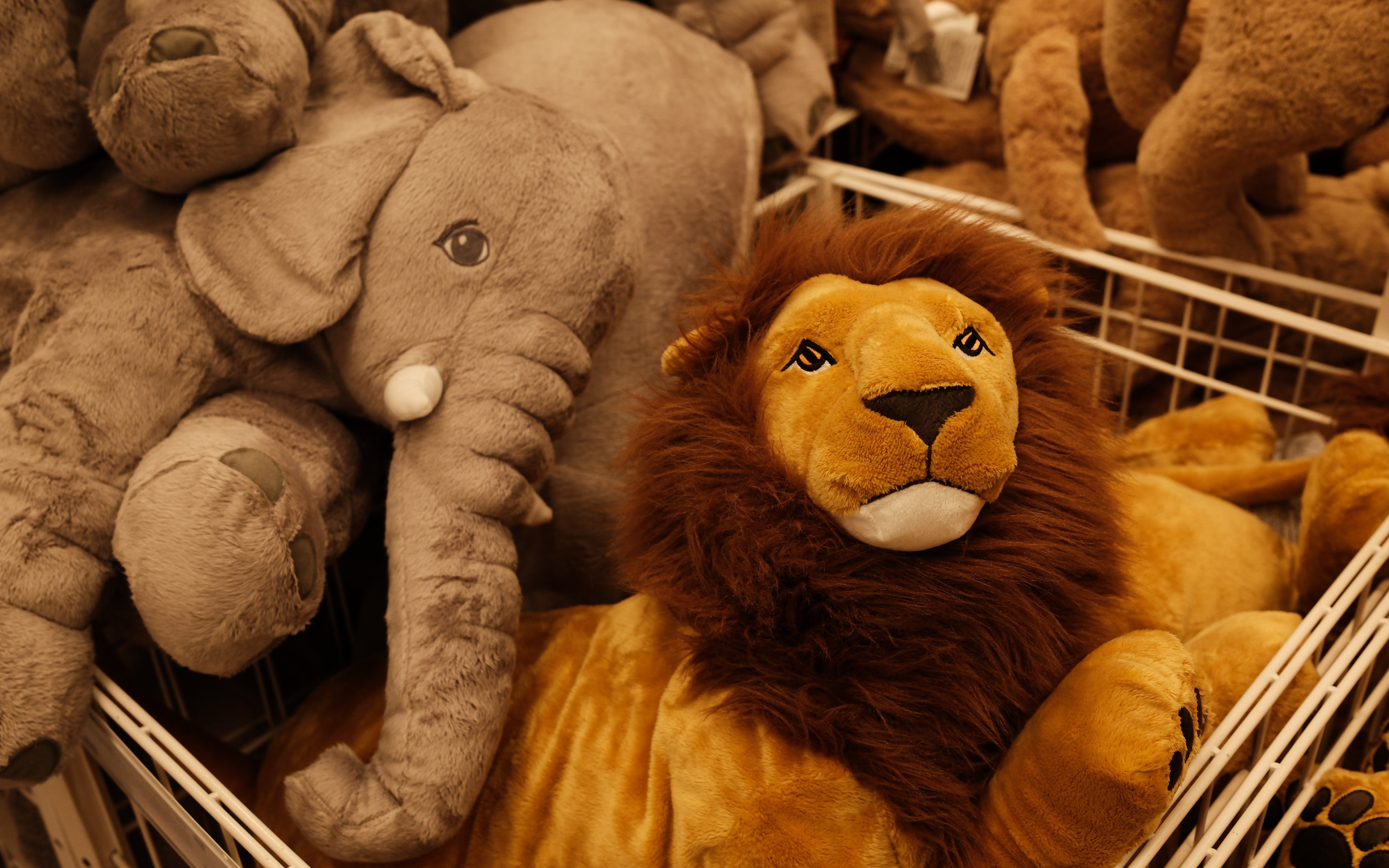 Stuffed lion and elephant toys in a soft toy store display.