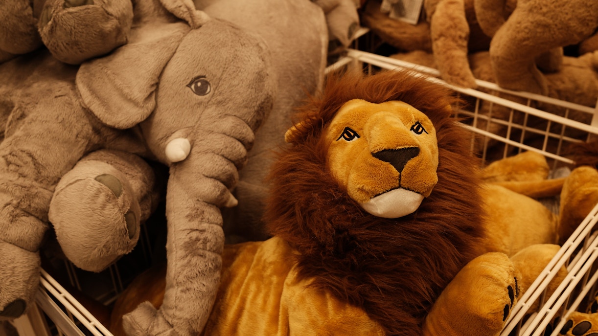 Stuffed lion and elephant toys in a soft toy store display.