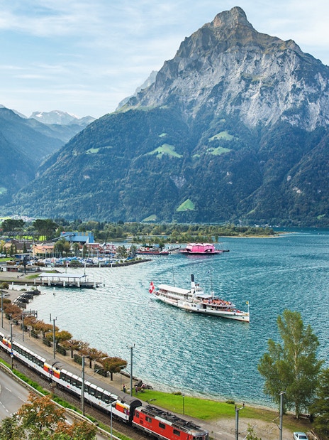 Train and boat on Lake Lucerne with Swiss Alps in the background.