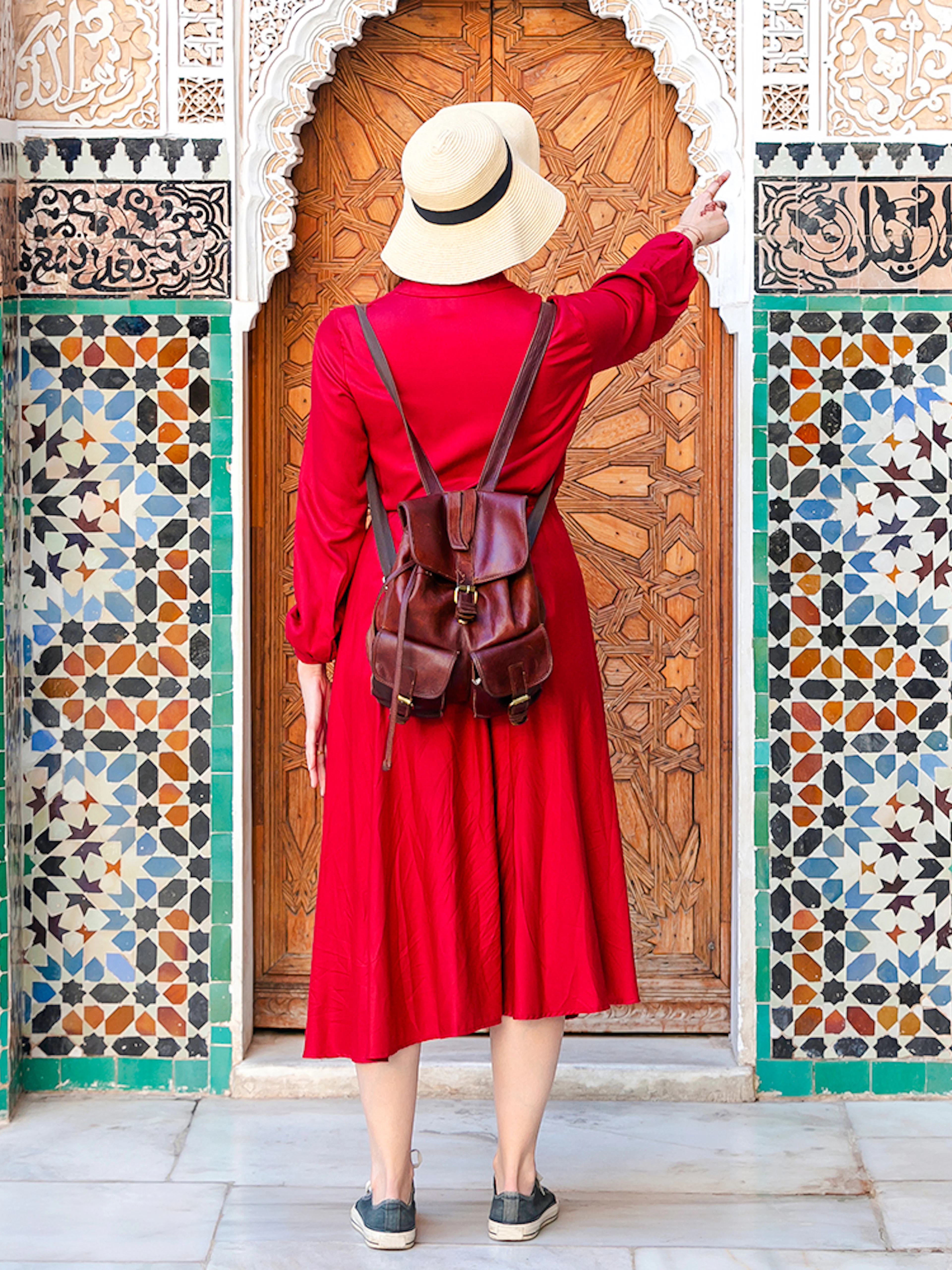 Lady admiring intricate tilework at Ben Youssef Madrasa, Marrakesh, Morocco.