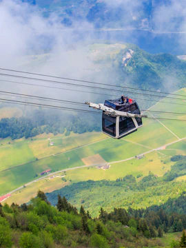 Stanserhorn cable car ascending over lush green landscape in Switzerland.