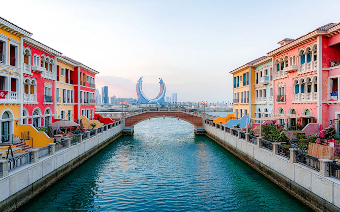 Colorful buildings and a bridge over a canal at The Pearl Island, Qatar.