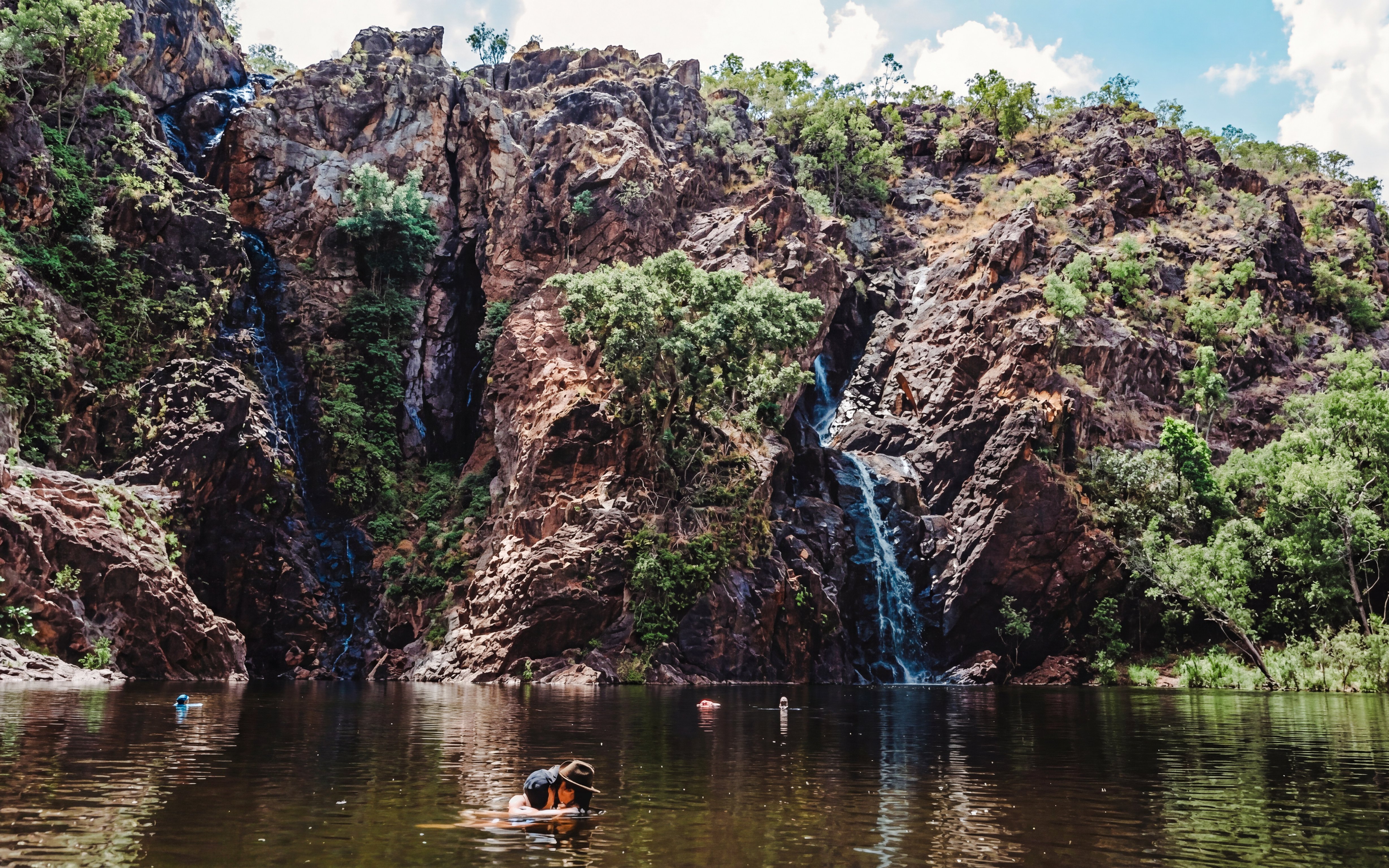 Waterfall cascading down rocky cliffs into a swimming area at Litchfield National Park.