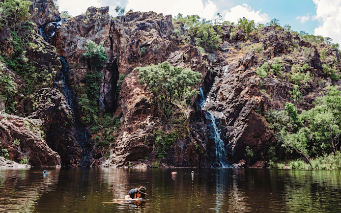 Waterfall cascading down rocky cliffs into a swimming area at Litchfield National Park.