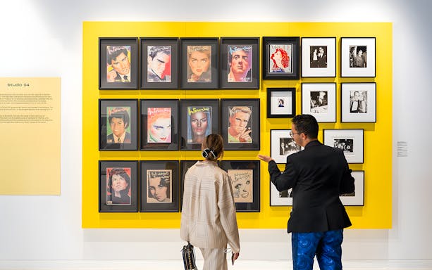 Visitors viewing Andy Warhol's Interview magazine covers at The Glam Factory exhibit.