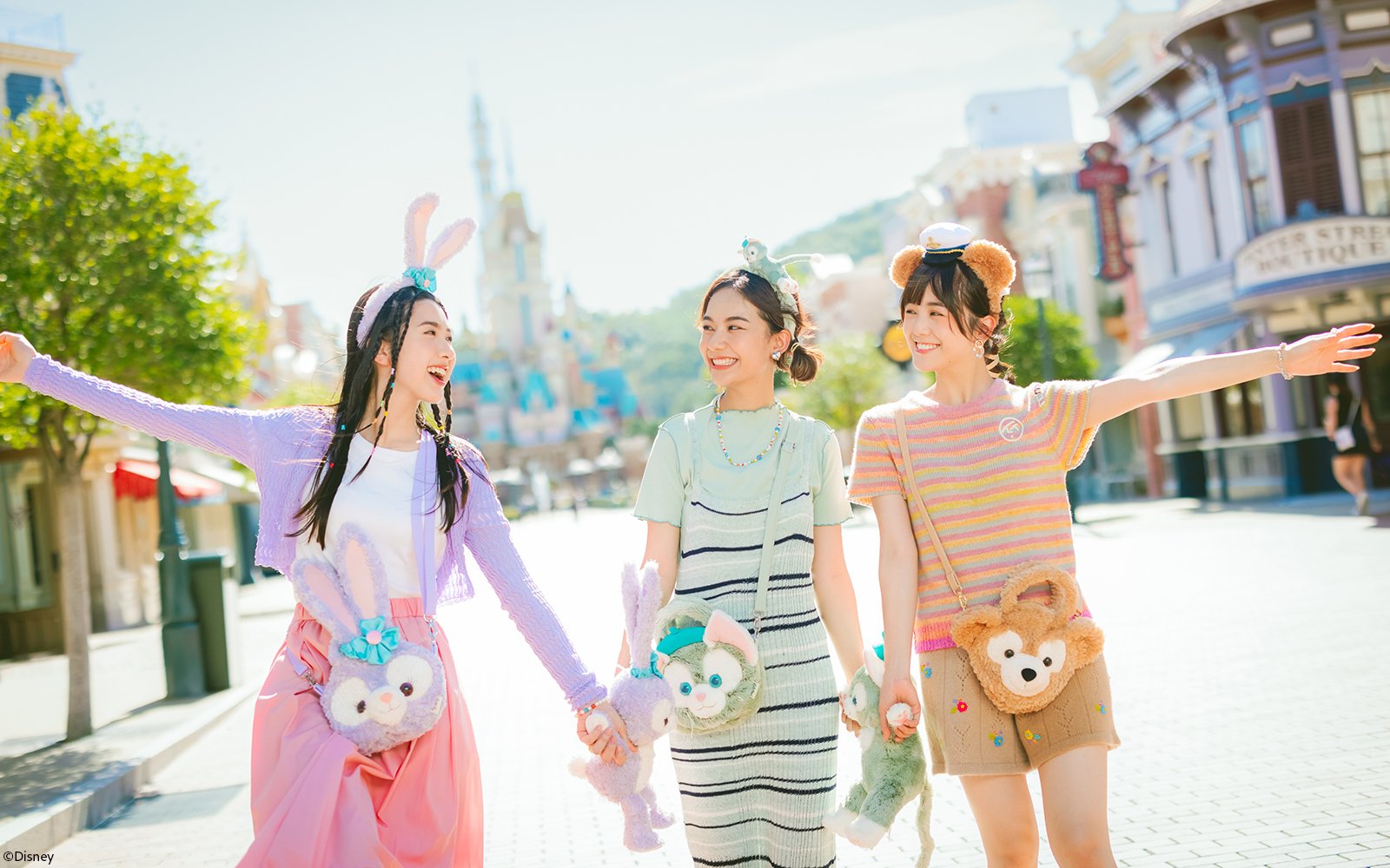 Tourists enjoying a sunny day at Hong Kong Disneyland with plush character bags.