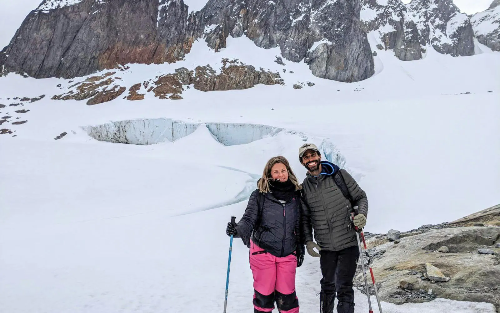 Trekking at Ojo del Albino Glacier with snow-covered mountains in the background.
