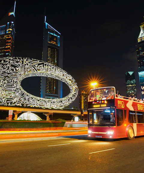 Big Bus Dubai Night Tour passing the Museum of the Future and skyscrapers.