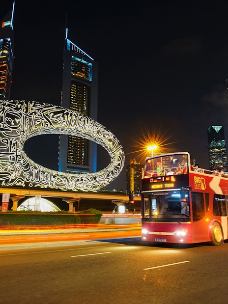 Big Bus Dubai Night Tour passing the Museum of the Future and skyscrapers.