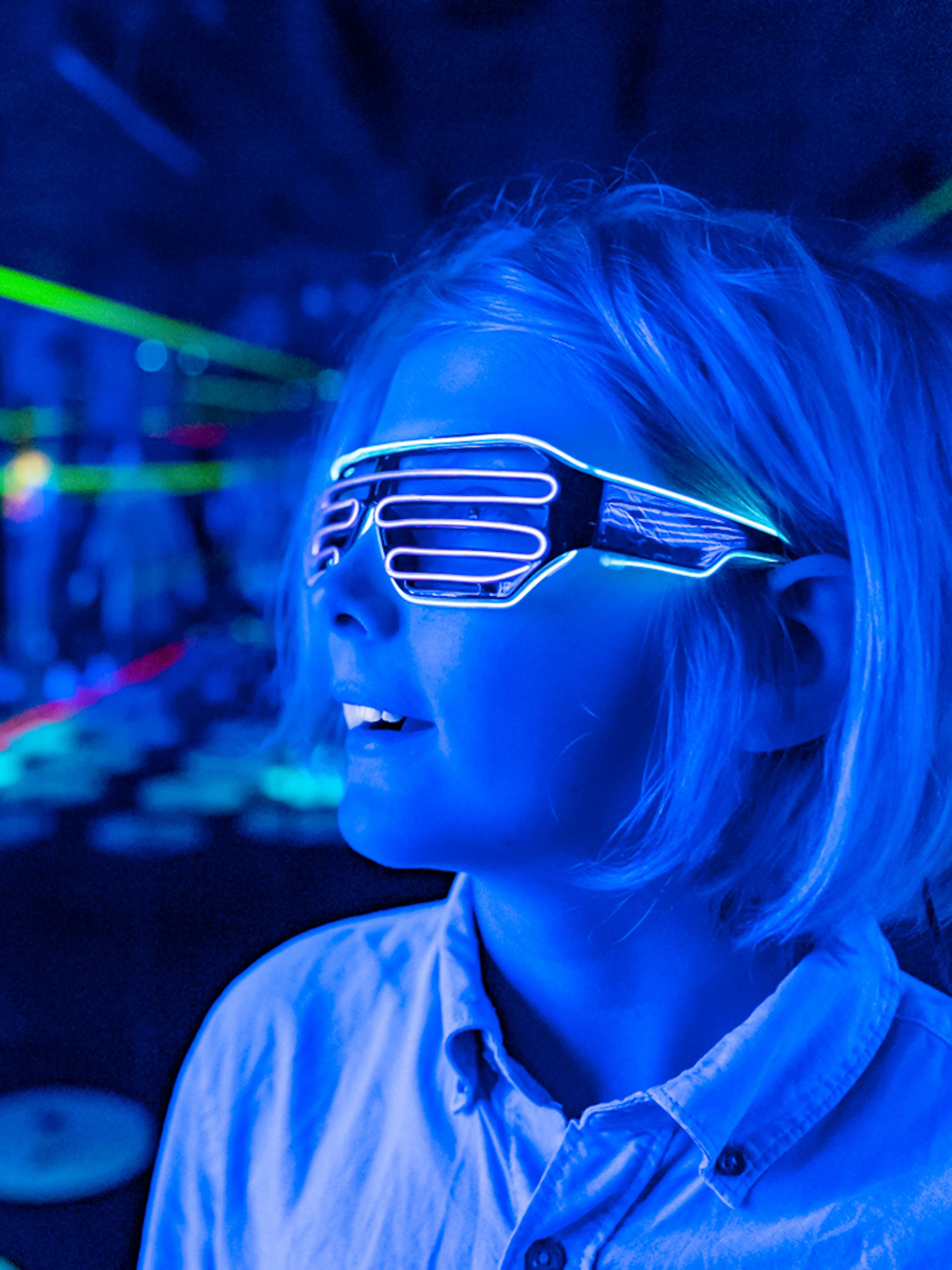 Child wearing LED glasses in a neon-lit room at Infinity Attraction, Gold Coast.