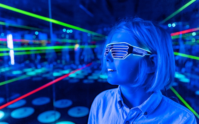 Child wearing LED glasses in a neon-lit room at Infinity Attraction, Gold Coast.