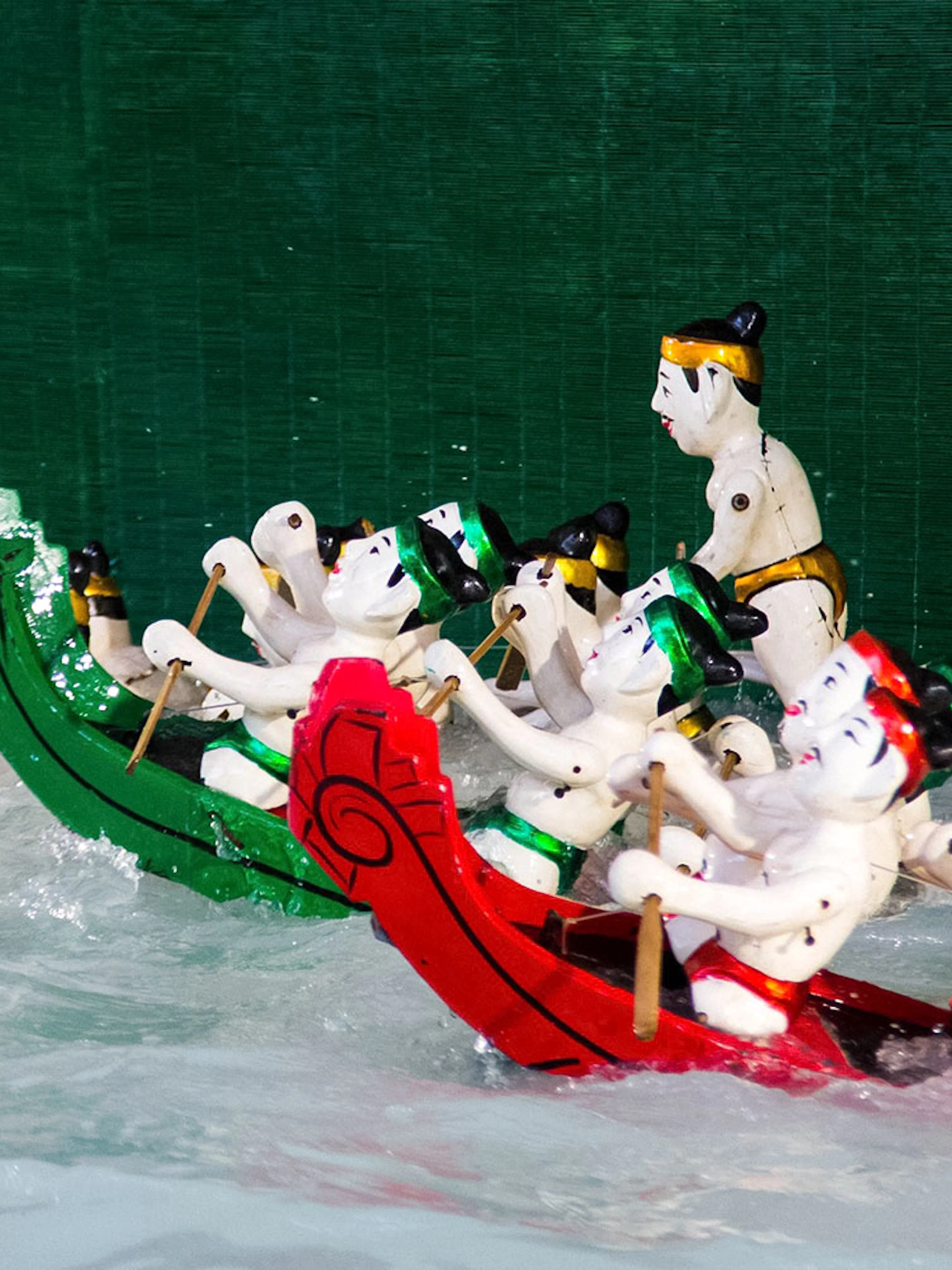 Water puppets in colorful boats performing at Golden Water Puppet Show.