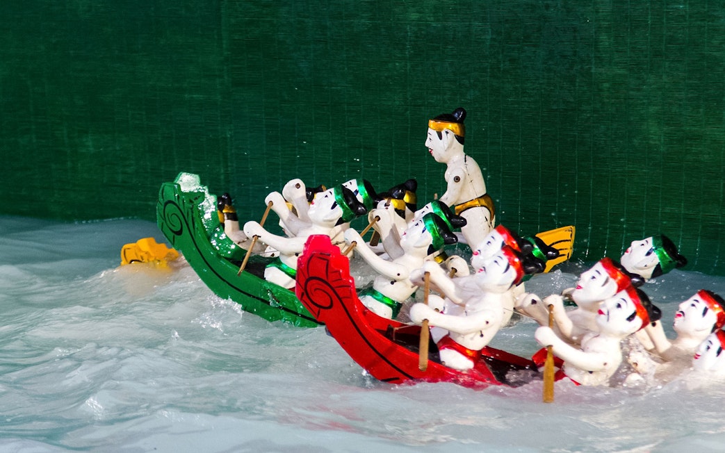 Water puppets in colorful boats performing at Golden Water Puppet Show.