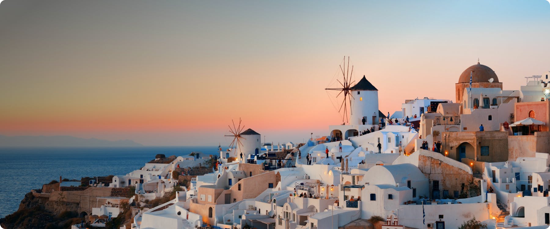 Sunset view of Oia village with windmills in Santorini, Greece.