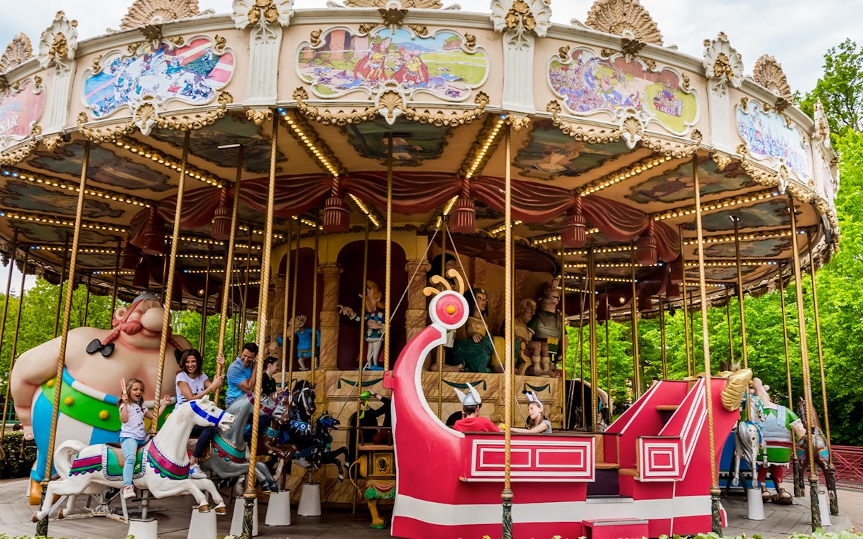 Carousel ride at Astérix Park with themed characters and families enjoying the attraction.