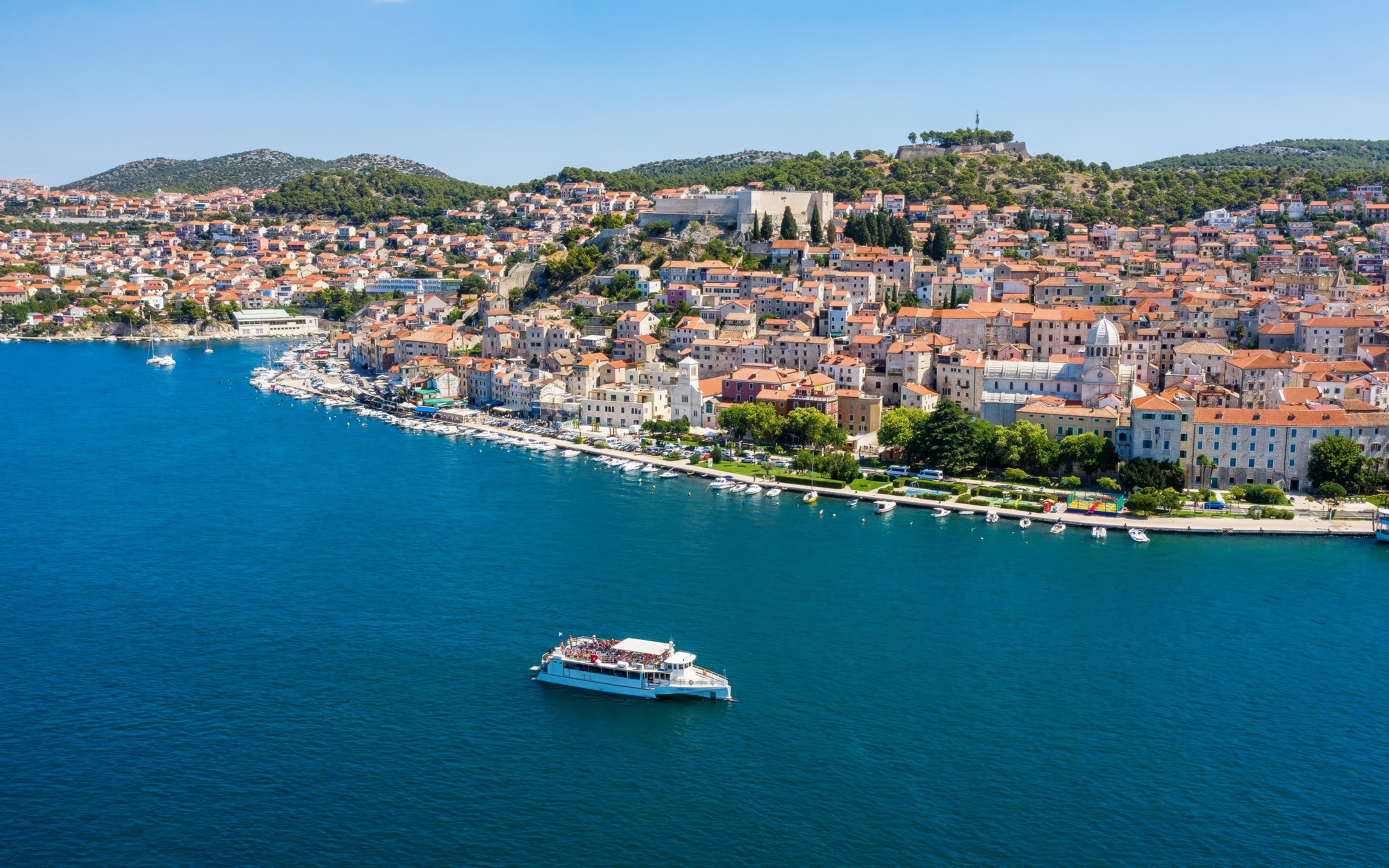 Aerial view of Sibenik Bay, Croatia, with a boat on the water and historic buildings along the coast.