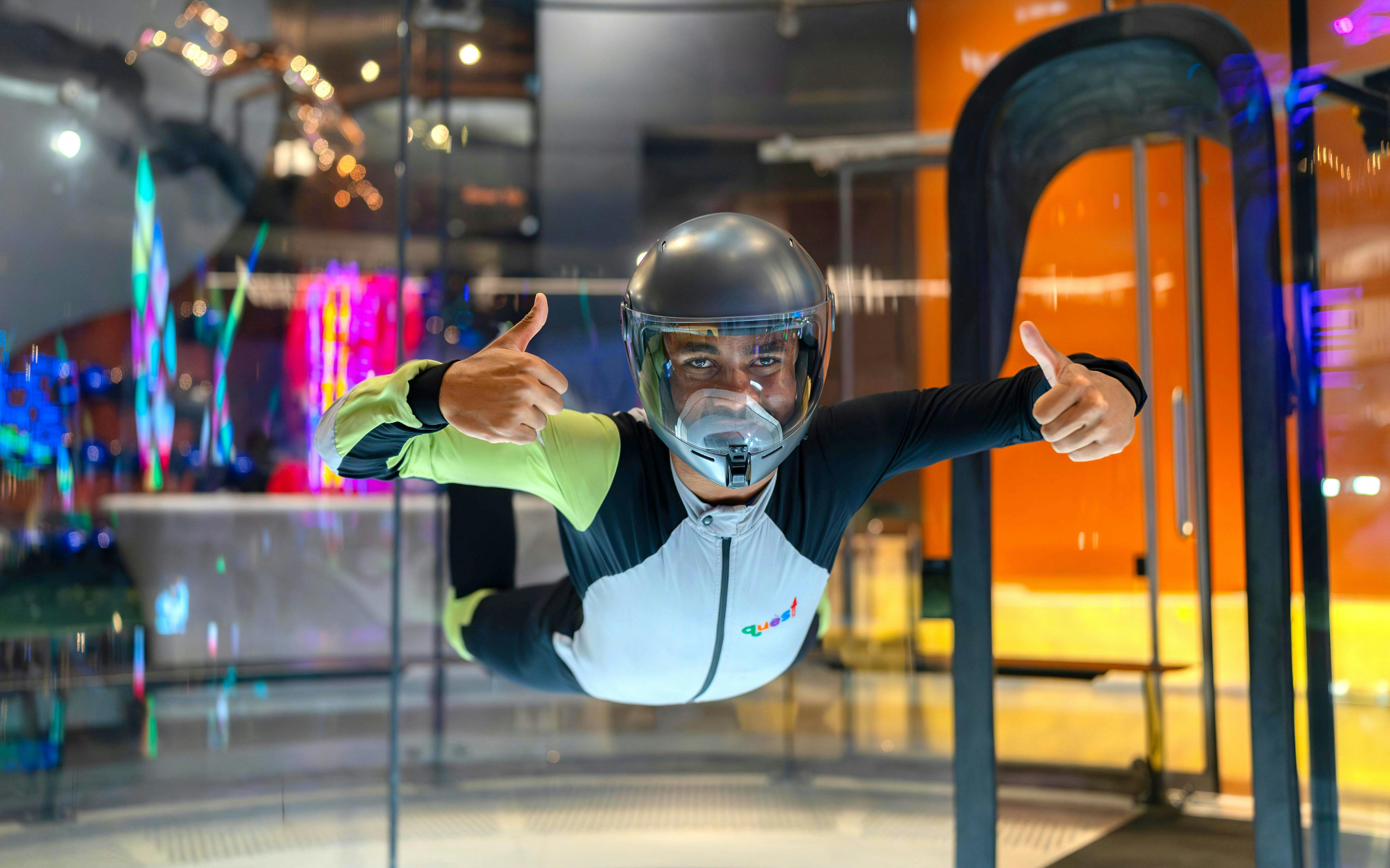 Person experiencing indoor skydiving at iFLY Quest, wearing a flight suit and helmet.