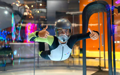 Person experiencing indoor skydiving at iFLY Quest, wearing a flight suit and helmet.