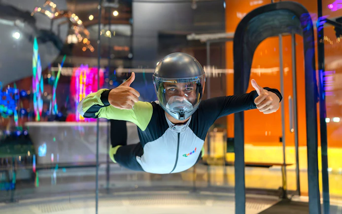 Person experiencing indoor skydiving at iFLY Quest, wearing a flight suit and helmet.