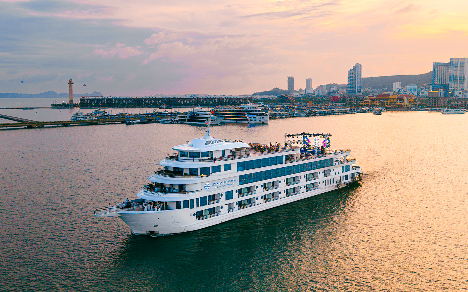 Aerial view of Ambassador cruise ship near city harbor at sunset.