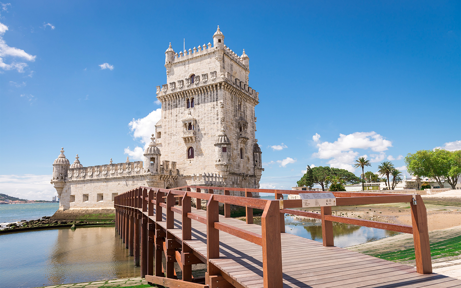 Belem Tower in Lisbon with wooden walkway and blue sky.