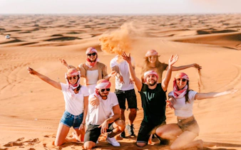 Group enjoying Abu Dhabi desert safari with camel ride and sandboarding.