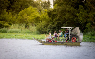 Small airboat with tourists exploring a swamp near New Orleans.