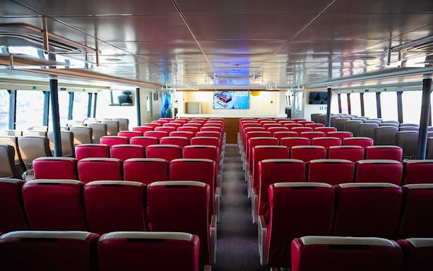 Interior seating of Majestic Fast Ferry with red chairs and large windows.