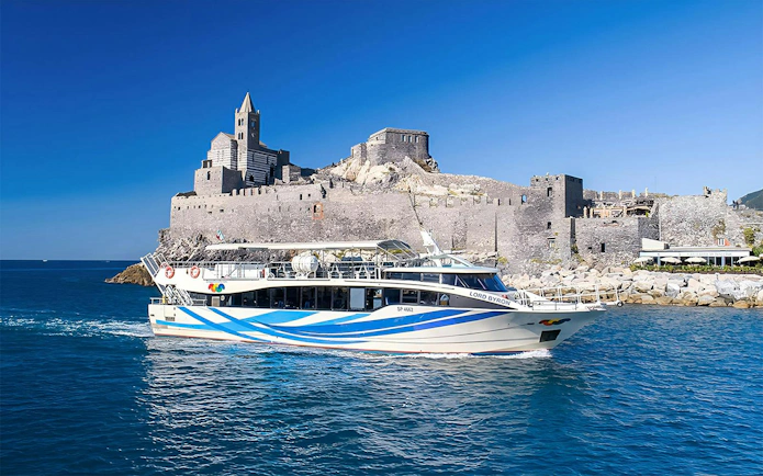 Cruise boat near historic castle in Cinque Terre, Italy.