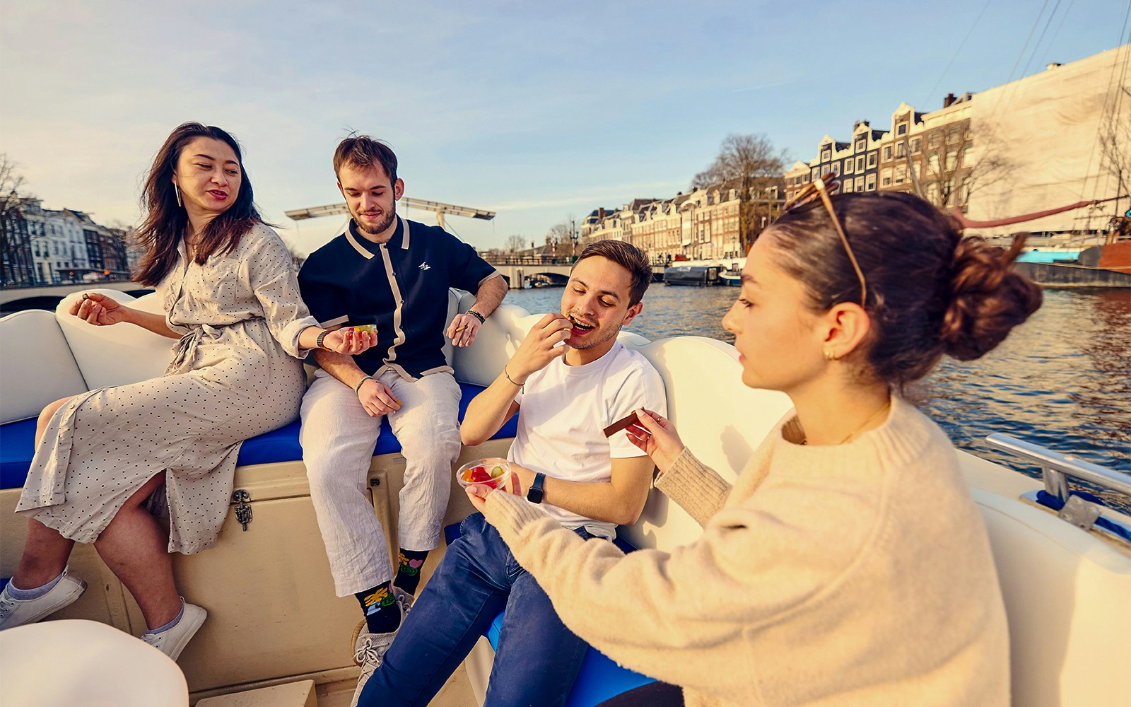 Guests enjoying the Cloud Boat Cruise on Amsterdam's canals with cityscape views.