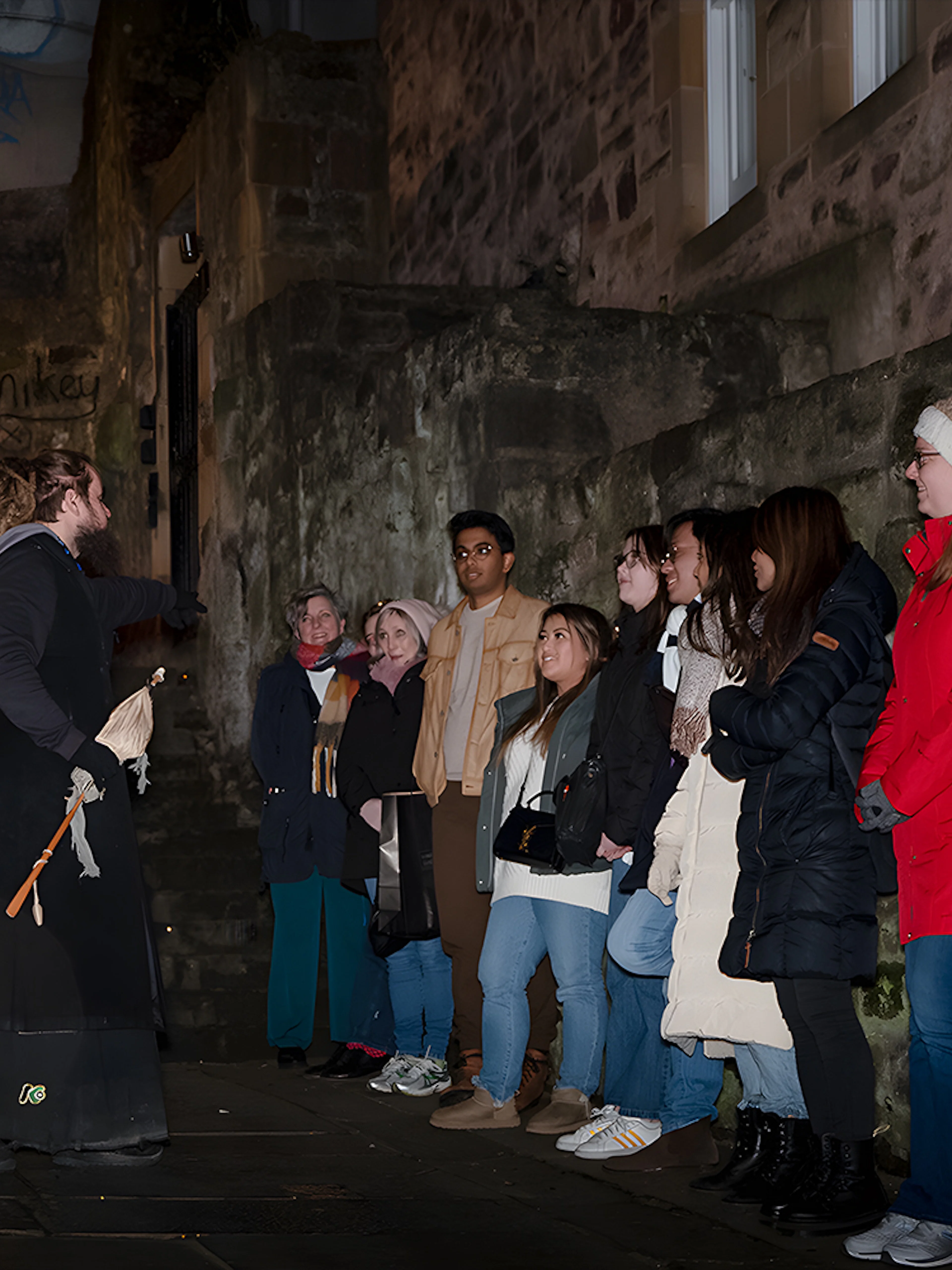 Tour guide leading a group on an Extreme Paranormal Activity Tour in a dimly lit alley.