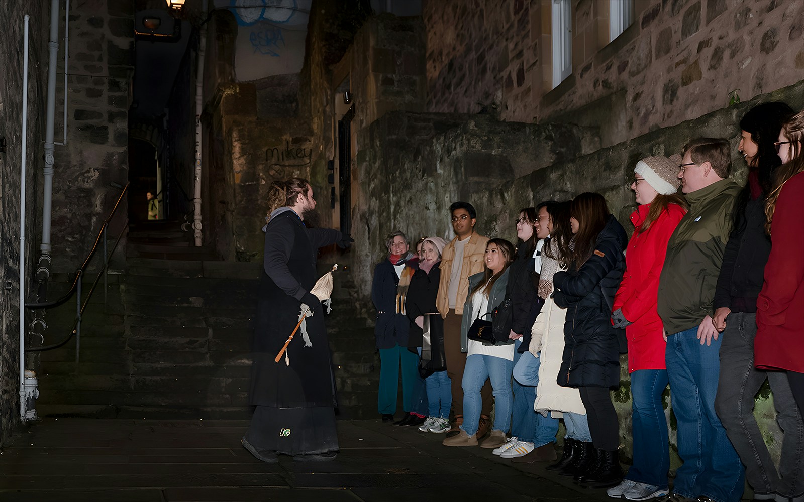 Tour guide leading a group on an Extreme Paranormal Activity Tour in a dimly lit alley.