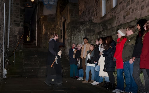 Tour guide leading a group on an Extreme Paranormal Activity Tour in a dimly lit alley.