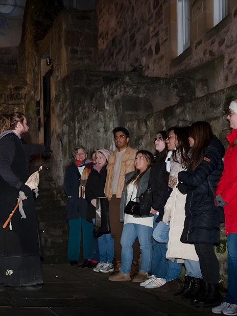 Tour guide leading a group on an Extreme Paranormal Activity Tour in a dimly lit alley.