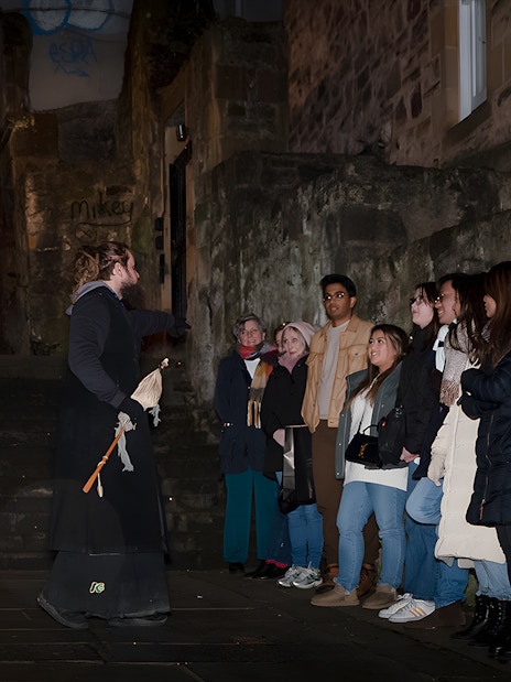 Tour guide leading a group on an Extreme Paranormal Activity Tour in a dimly lit alley.